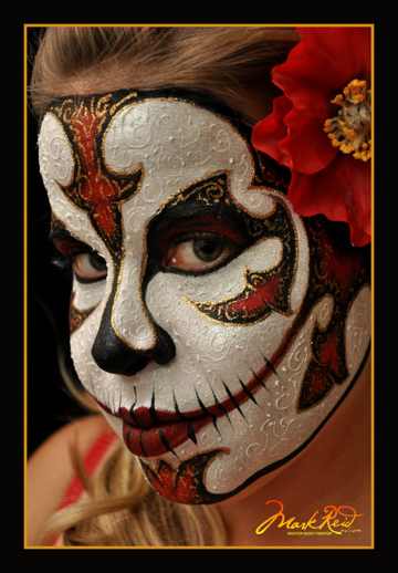 girl that is wearing a full face painting which looks has a skull theme but there is a lot of white on white highlights that are raised that appear to be pearlized